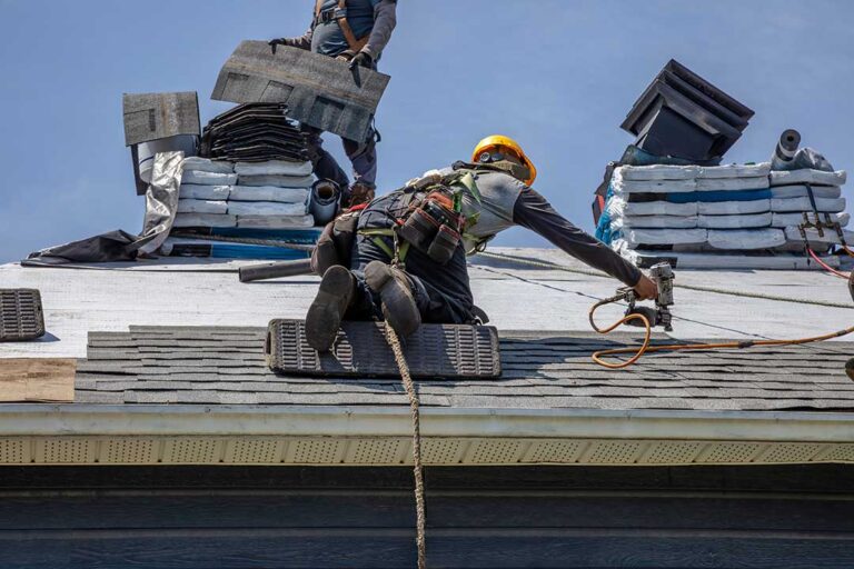 A close-up of misaligned asphalt shingles and exposed nails on a residential roof.